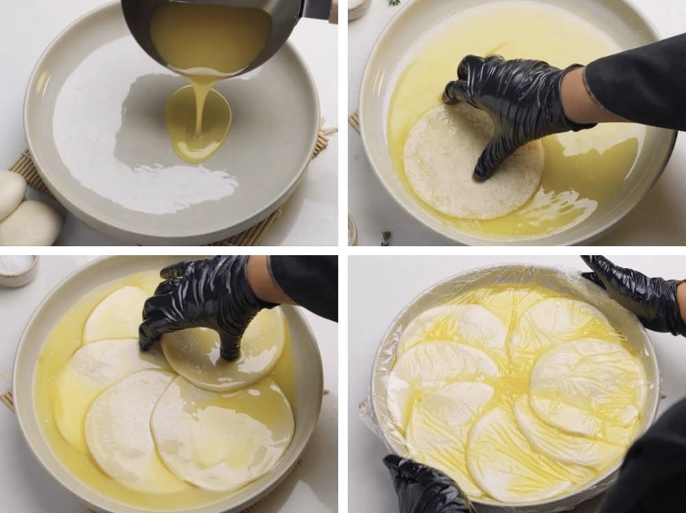 Turkish borek Alt text: Dough balls soaking in a rich butter and oil mixture resting in a tray under cling wrap