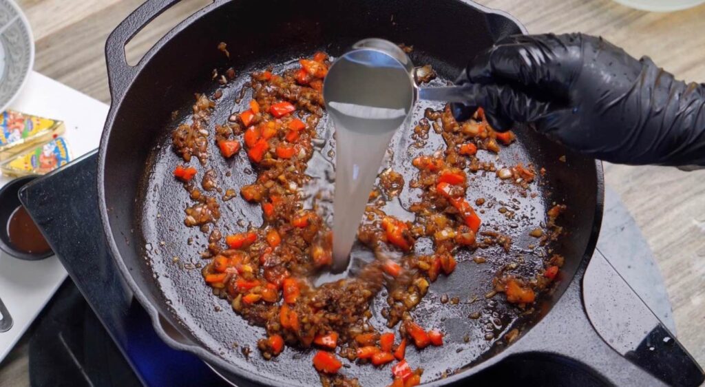 Add the pasta water A small measuring cup pouring starchy pasta water into a creamy sauce simmering in a skillet, helping everything come together.