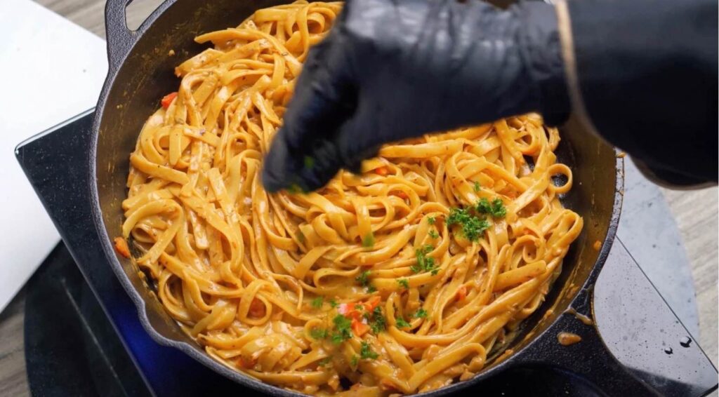 Add the parsley Freshly chopped parsley being sprinkled over a bowl of creamy Cajun fettuccine, adding a fresh touch of color.