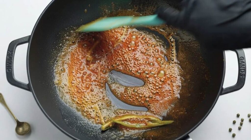 Cook butter and ginger Melted butter sizzling with julienned ginger, green chilies, and a pinch of red chili powder in a pan.