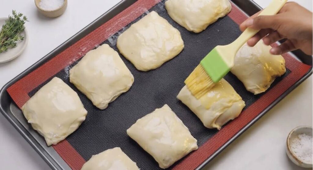 Turkish borek Shaped chicken börek rolls brushed with egg yolk arranged on a parchment-lined baking tray