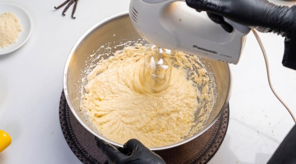 Eggs being added one at a time to the creamy butter and brown sugar mixture.