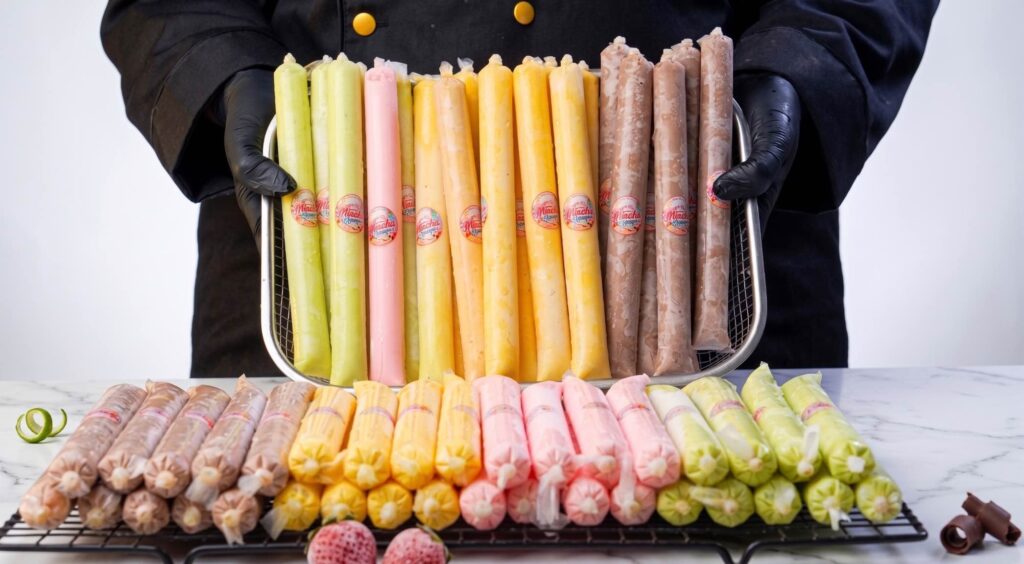 Creamy es mambo A pile of frozen Creamy Es Mambo icy poles inside small plastic tubes showing colorful marbled white chocolate designs.